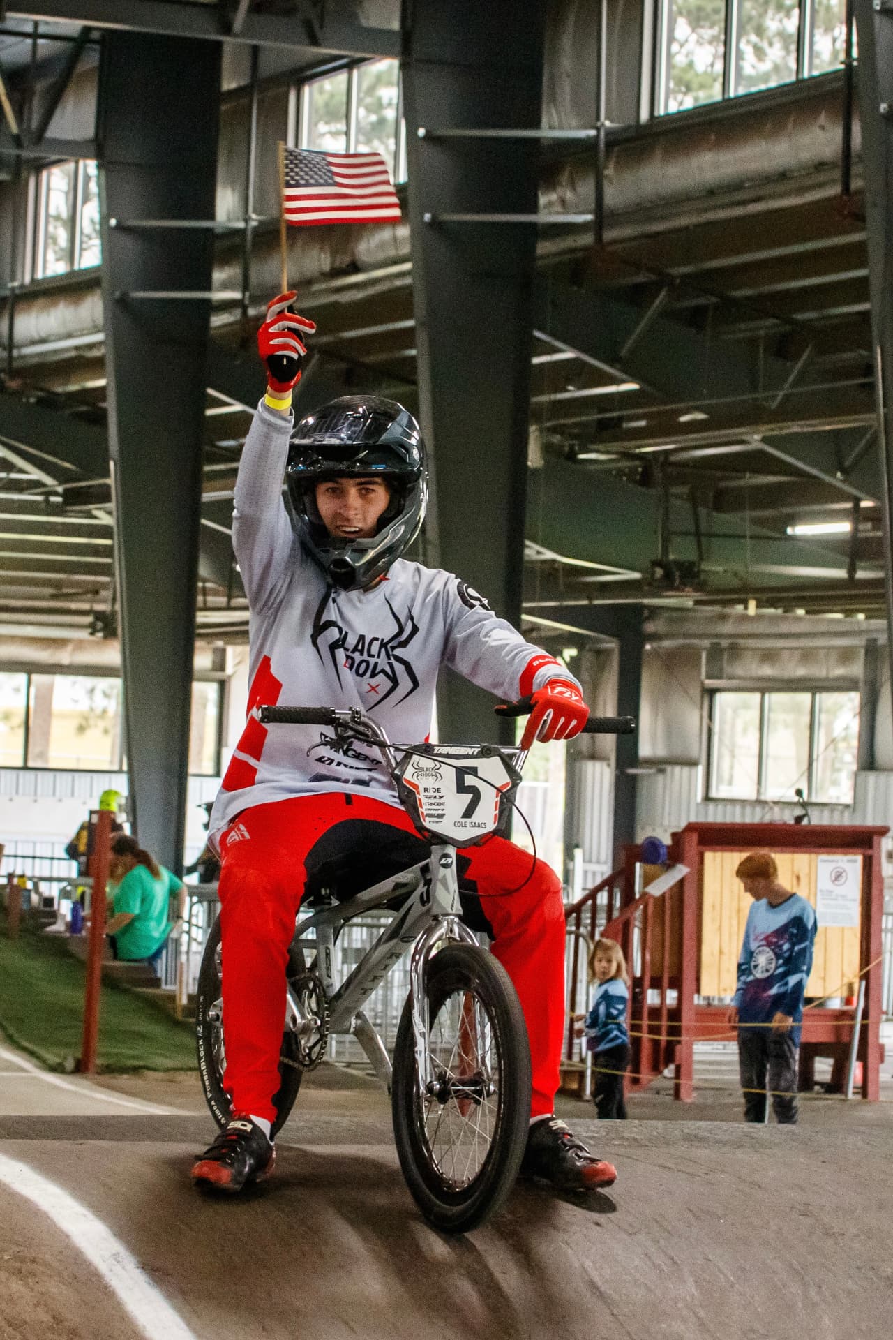 Cole Isaacs holding an American flag at the starting gate before a BMX race
